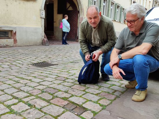Zwei Männer knien vor Stolpersteinen zum Gedenken an Nazi-Gräueltaten in der Ettlinger Altstadt