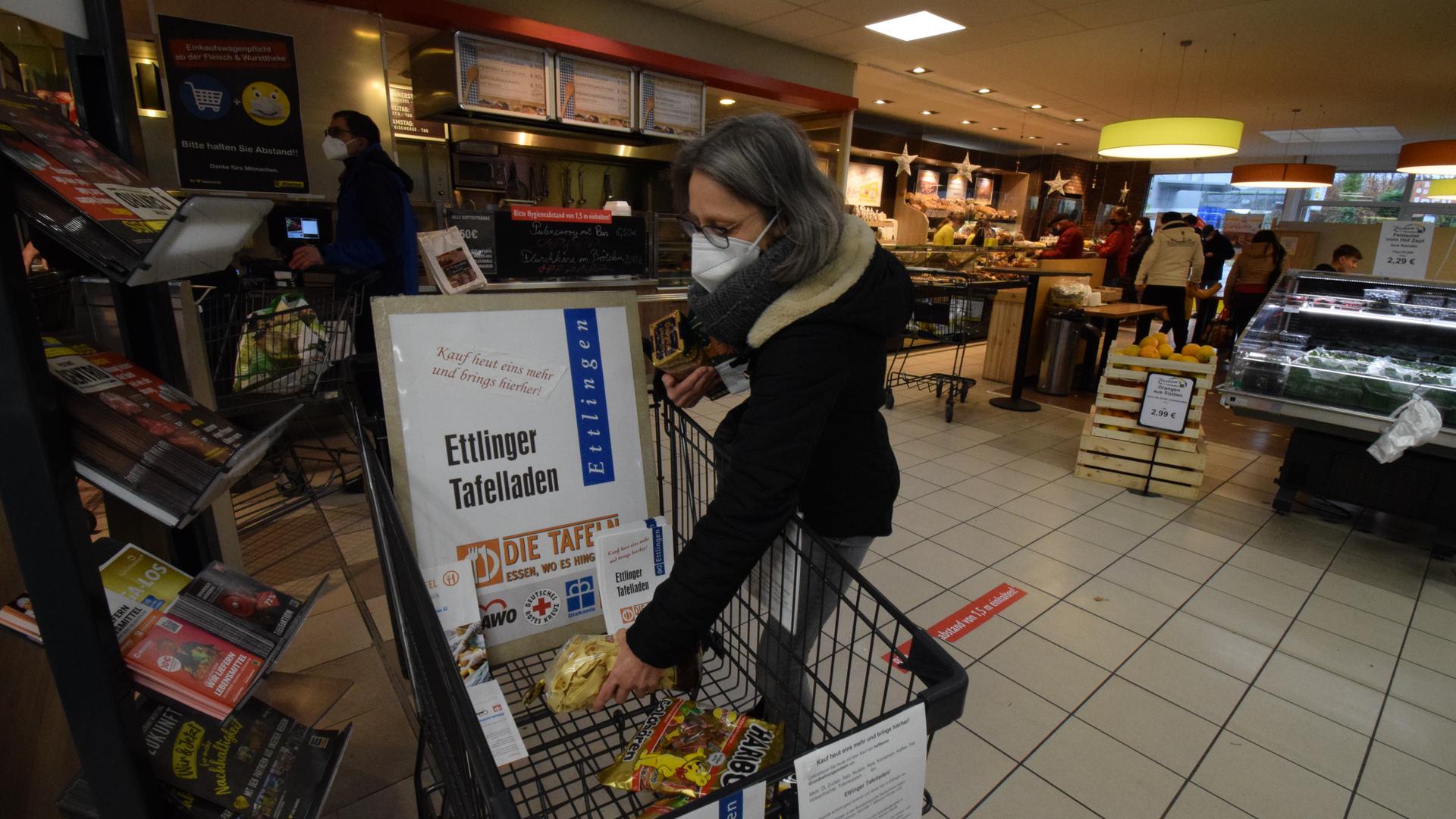 Helfen mit Lebensmittelspenden: Petra Schmieder legt im Edeka-Markt Nudeln, Spekulatius-Kekse und Kaffee in einen Einkaufswagen des Tafelladens.