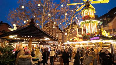 Besucher stehen auf dem Weihnachtsmarkt in Ettlingen, dem Sternlesmarkt, vor den Ständen und der Glühwein-Pyramide.