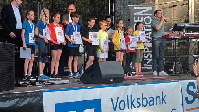 Vertreter der Volksbank Ettlingen bei der Siegerehrung für den Läufernachwuchs auf der Bühne