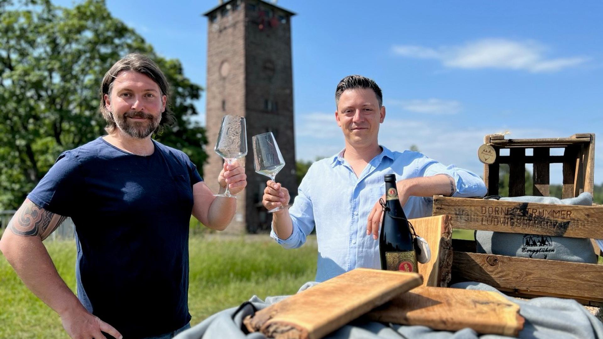 Zwei Männer stoßen mit Champagner vor einem Turm an 