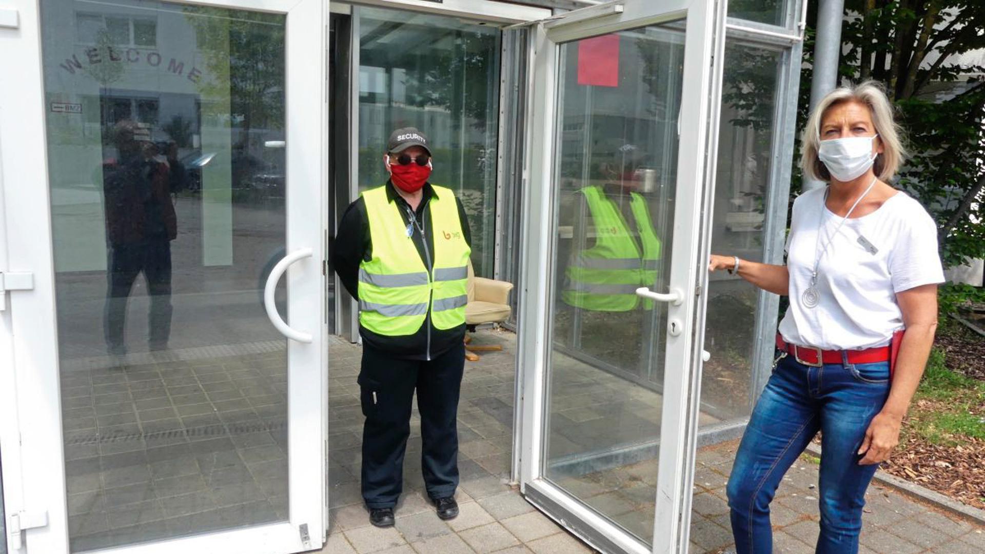 Unterkunftsleiterin Gabriele Germer (rechts) und der Mitarbeiter eines privaten Sicherheitsdienstes stehen am Eingang zur Quarantäne-Station.