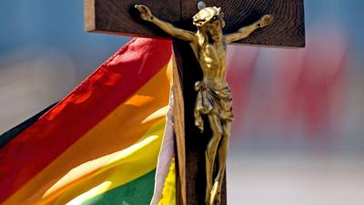 Jesus am Kreuz mit Regenbogenfahne im Hintergrund