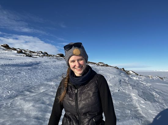 Alicia Rohnacher steht auf einer Eisfläche in der Antarktis und lächelt in die Kamera.