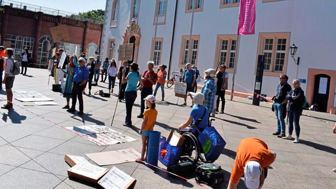 Mit Plakaten demonstrierten 50 Menschen vor dem Ettlinger Schloss für die Aufhebung der Maßnahmen zur Eindämmung des Coronavirus.