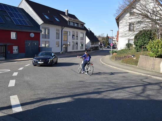 Eine Radfahrerin will von der Richard-Wagner-Straße in Malsch nach links in die Neudorfstraße einbiegen. Sie wartet in der Mitte der Fahrbahn, bis ein Auto im Gegenverkehr vorbeigefahren ist. 