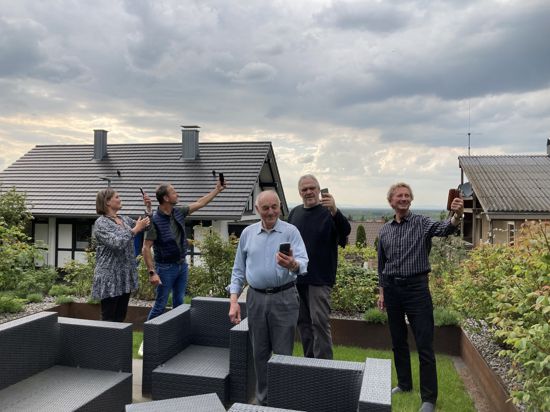 Anwohner von Sulzbach stehen mit Handys auf der Terrasse.