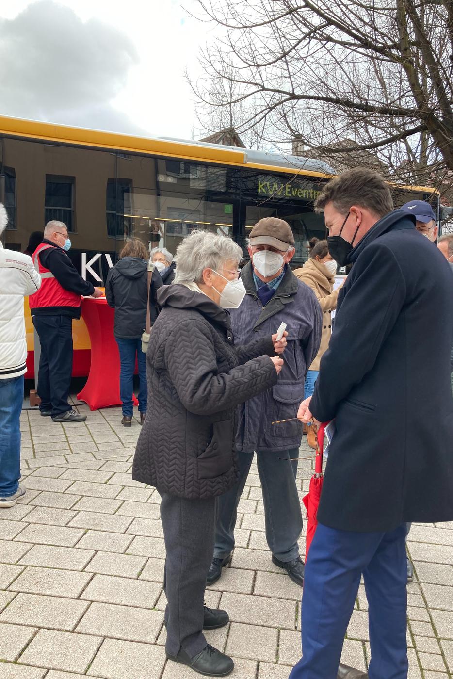 KVV-Geschäftsführer Alexander Pischon (rechts) im Gespräch mit einem älteren Ehepaar vor dem Schulungsbus auf dem Mühlenplatz in Malsch.