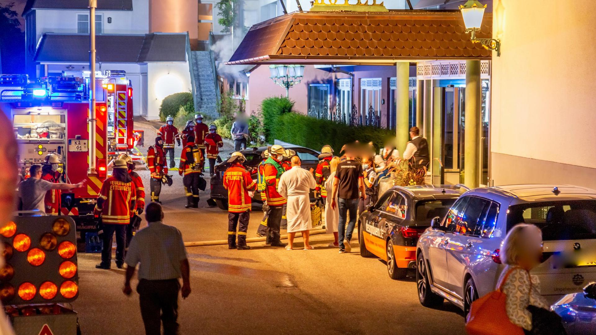 Feuerwehrleute und Hotelgäste stehen vor dem Eingang des Hotels in Ettlingen.