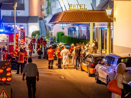 Feuerwehrleute und Hotelgäste stehen vor dem Eingang des Hotels in Ettlingen.
