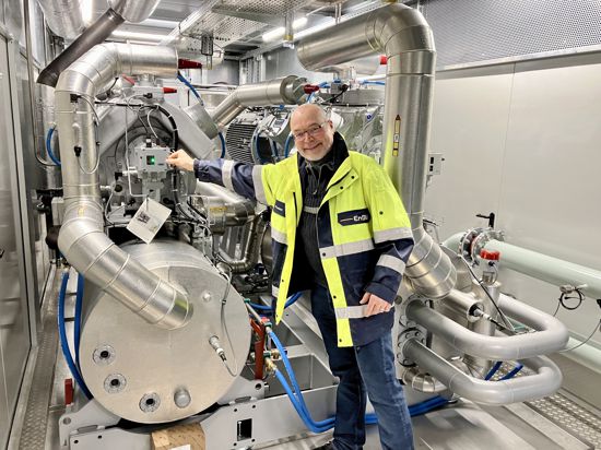 EnBW-Projektleiter Wolfgang Frenzel zeigt auf riesige Maschinen und Rohre, die Teil einer neuen Wärmepumpe sind.