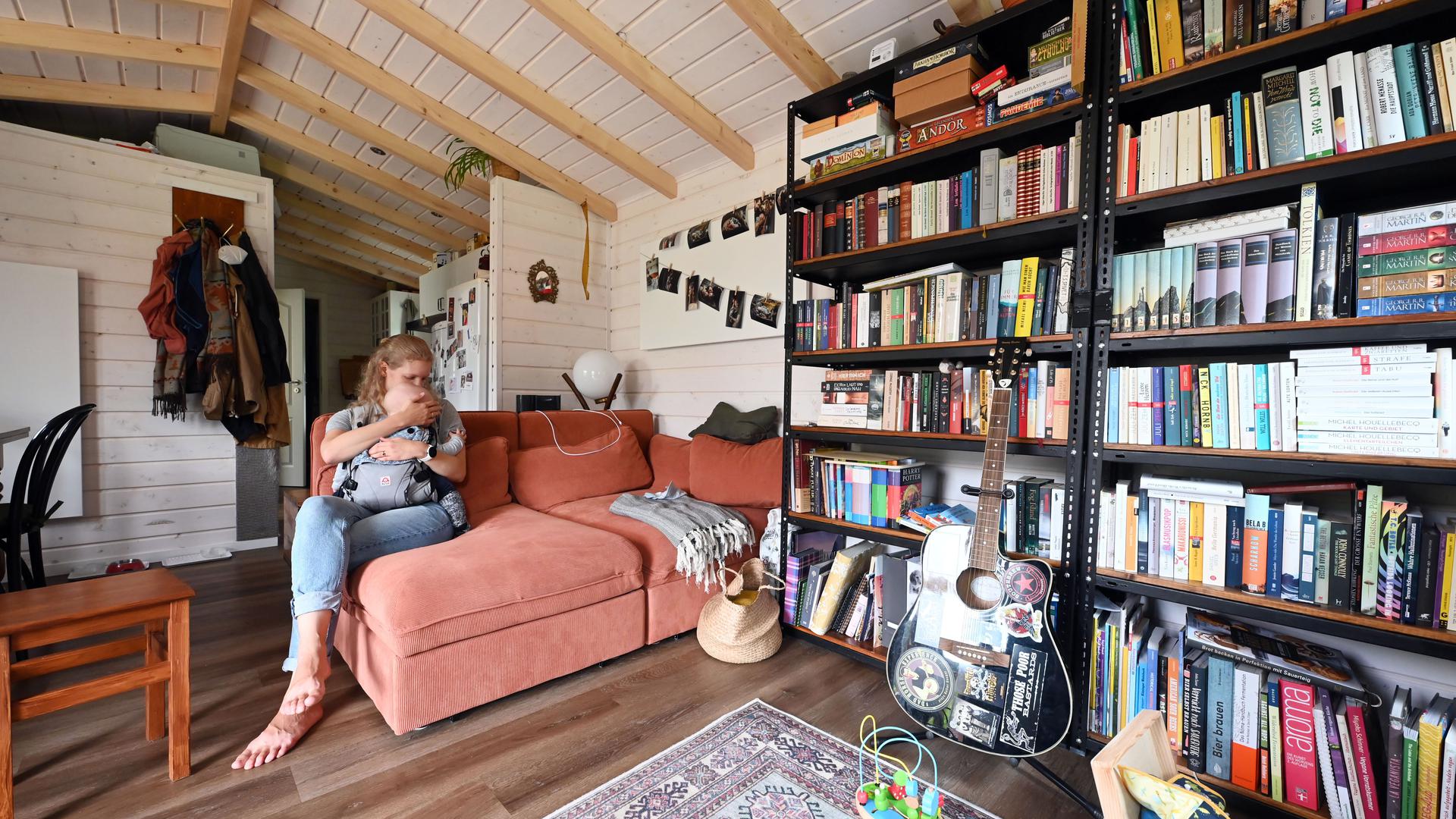 PRODUKTION - 27.06.2022, Baden-Württemberg, Waldbronn: Larissa Pferdmenges sitzt mit ihrem Kind in ihrem Tiny House auf dem Campingplatz Albtal. Tiny Houses - Minihäuser - gibt es inzwischen überall in Deutschland. Noch sind es nicht viele, denn passende Grundstücke sind rar. (zu dpa-Korr «Wohnen - Tiny Houses sind Trend und bleiben Nische») Foto: Uli Deck/dpa +++ dpa-Bildfunk +++