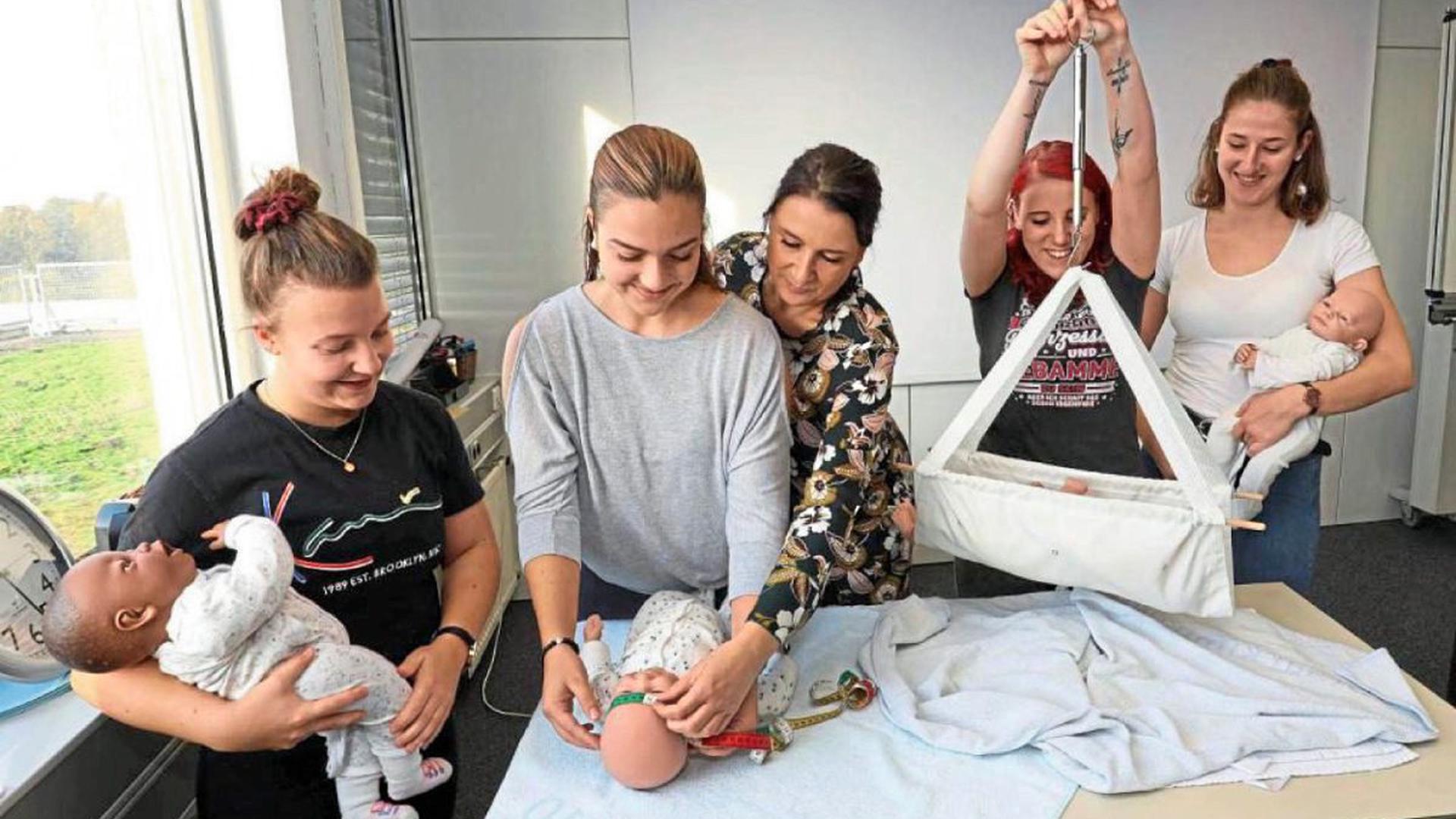 Die Vermessung der Neugeborenen zählt zu den Aufgaben der Hebammen im Kreißsaal. In der Hebammenschule Karlsruhe zeigt Stephanie Dietrich (Mitte) den Schülerinnen an Babypuppen, worauf sie achten müssen.