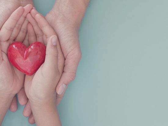 Adult and child hands holding red heart, organ donation, wellbeing, family health insurance and CSR concept, world heart day, world health day