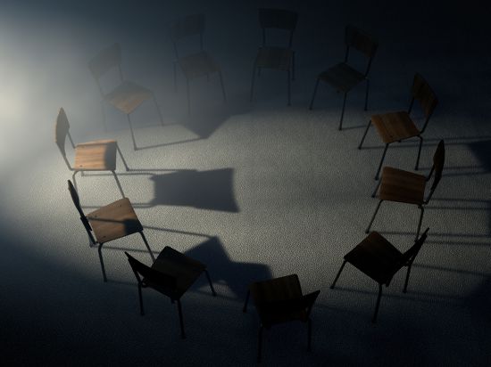 Stühle stehen in einem Kreis in einem dunklen Raum.