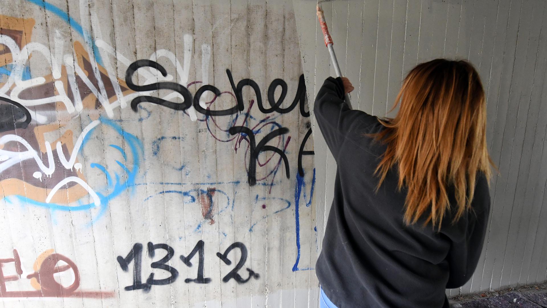 Eine Jugendliche beseitigt in einer Unterführung in Graffitis. 