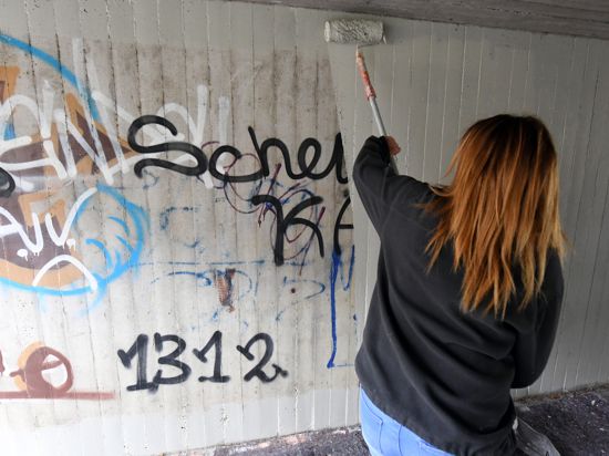 Eine Jugendliche beseitigt in einer Unterführung in Graffitis. 