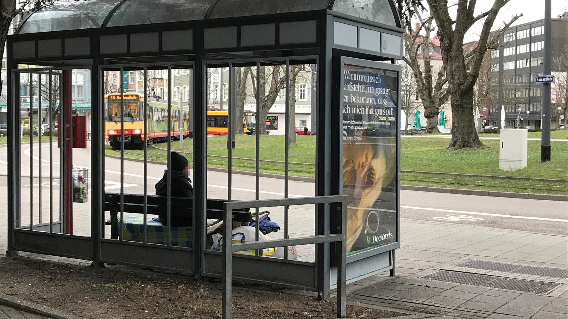 Ein wohnungsloser Mann sitzt seit Wochen an einer Bushaltestelle am Mühlburger Tor.