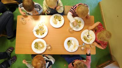 Kinder einer Kinderkrippe essen ein vegetarisches Mittagessen. 