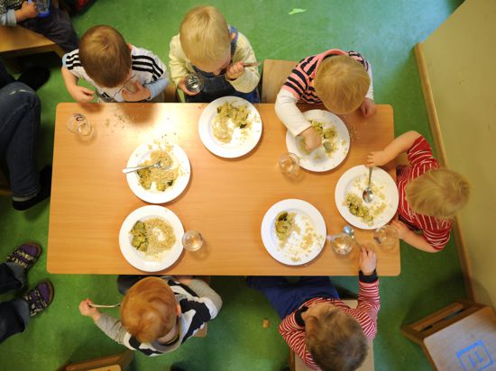 Kinder einer Kinderkrippe essen ein vegetarisches Mittagessen. 