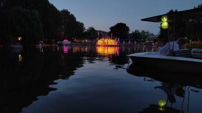 Blick auf den See im Karlsruher Zoo. Im Hintergrund ein leuchtender Mississippi-Dampfer.