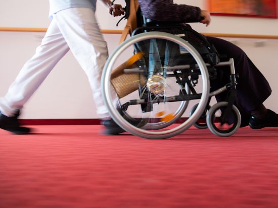 Ein Pfleger eines Pflegeheims schiebt eine Bewohnerin mit einem Rollstuhl. (zu dpa «Anwerbung ausländischer Pflegekräfte stockt wegen Corona») +++ dpa-Bildfunk +++