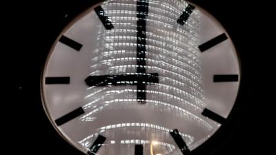 Die Uhr am Verkehrsturm am Potsdamer Platz zeigt 21:00 Uhr, wobei sich ein Bürogebäude darin spiegelt. +++ dpa-Bildfunk +++