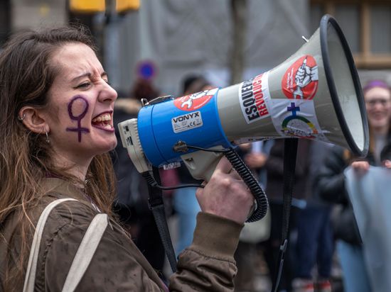 Eine Frau mit dem Weiblichkeitszeichen am Gesicht spricht über ein Megafon während einer Kundgebung anlässlich des Internationalen Frauentags. +++ dpa-Bildfunk +++