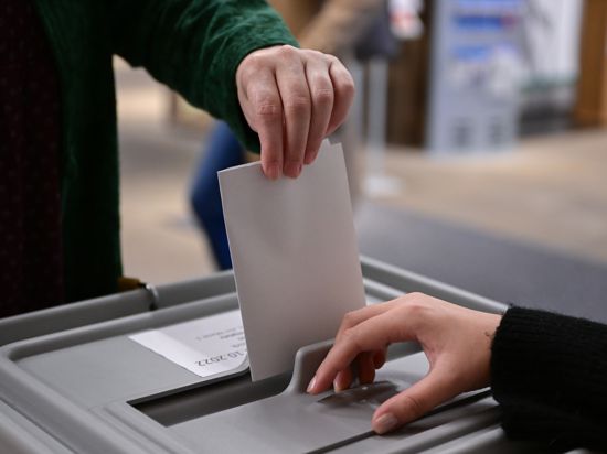 Ein Wähler steckt seinen Wahlzettel in eine Urne