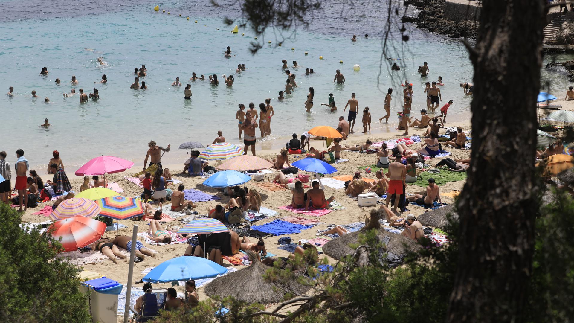Menschen schwimmen und sonnen sich am Strand von Illetes auf Mallorca. 