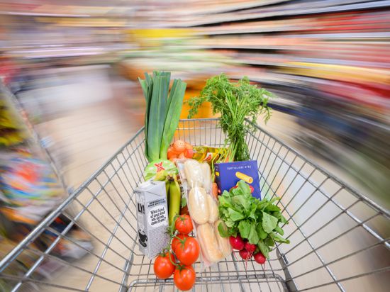 Ein mit Lebensmittel gefüllter Einkaufswagen wird durch einen Supermarkt geschoben (gestellte Szene, Aufnahme mit langer Verschlusszeit). (Zu dpa "Einkäufe für Verbraucher teurer, reale Umsätze für Händler rückläufig") +++ dpa-Bildfunk +++