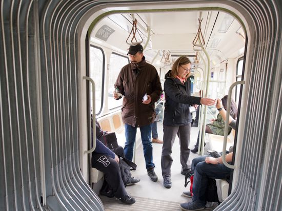  Mitarbeiter des Fahrausweis-Prüfdienstes überprüfen Fahrscheine  in einer Stadtbahn.