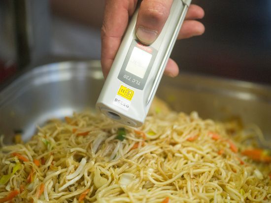 Ein Lebensmittelkontrolleur überprüft die Temperatur von chinesischen Nudeln.