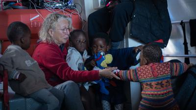 Frau auf Rettungsschiff mit Kindern.