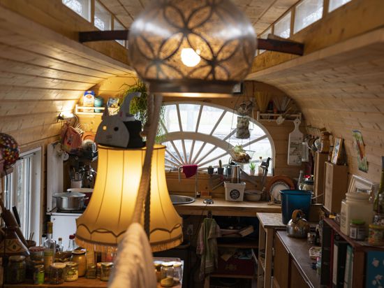 Im Innern eines Bauwagens sind Wohn- und Küchenutensilien zu sehen. Im Vordergrund stehen zwei Lampen mit warmen Licht.
