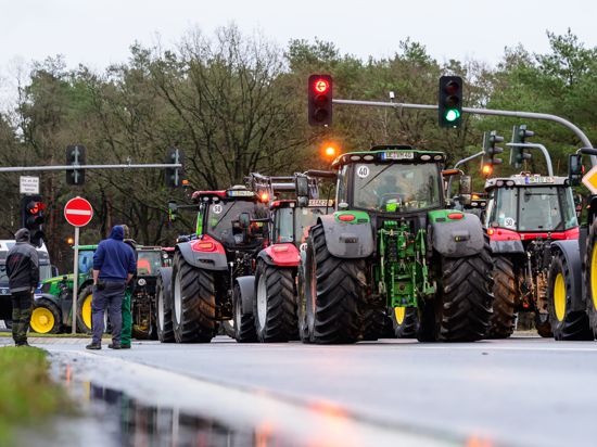 Landwirte blockieren mit ihren Treckern eine Straße.