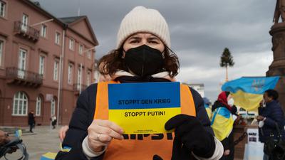 Eine Frau hält auf der Mahnwache ein kleines Schild hoch: „Stoppt den Krieg, stoppt Putin!“ ist darauf zu lesen.