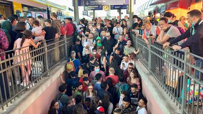 Nichts geht mehr: Menschen drängen am Karlsruher Hauptbahnhof auf einer überfüllten Treppe in beide Richtungen. Eine DB-Mitarbeiterin versucht, für Ordnung zu sorgen.