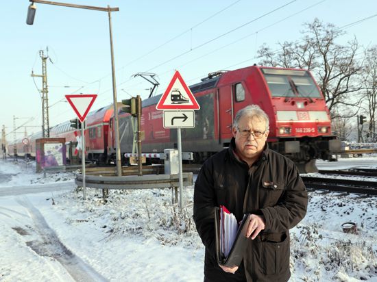 Rentner mit Aktenordner vor einem Bahnübergang.