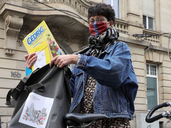 CCFA-Volontärin Cloé Miglioli packt eine Bestellung von Büchern aus der Mediathek in ihre Fahrradtasche.