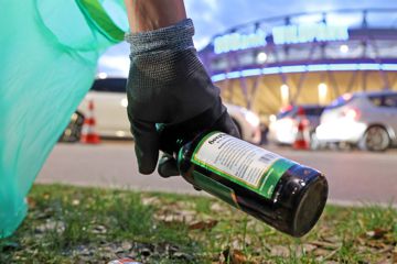 Hand hebt Flaschen vor KSC-Stadion auf.