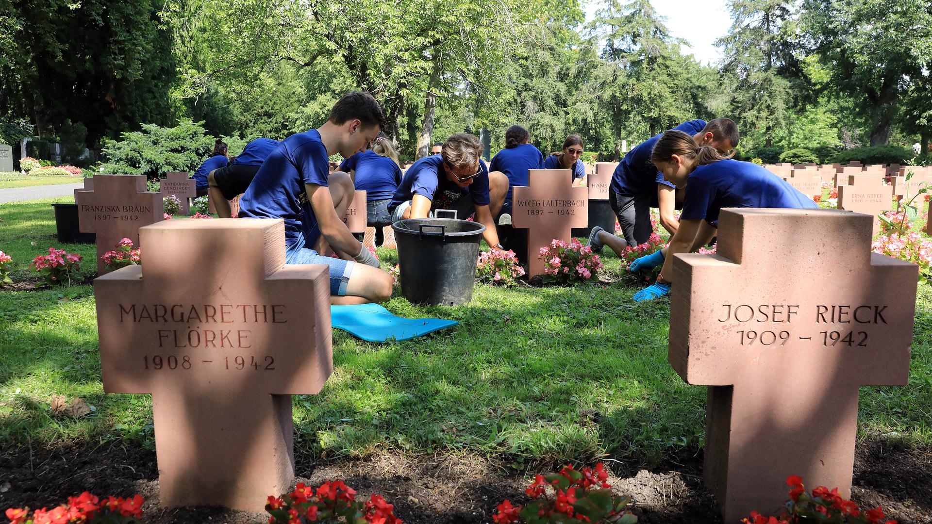 Jugendliche pflegen Gräber auf einem Friedhof