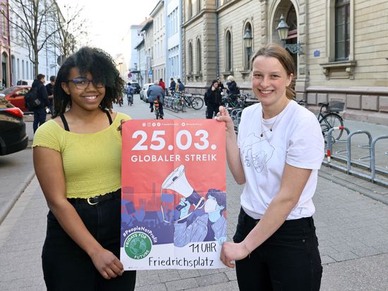 Am 24.03.2022 stehen Lilith Diaw (links) und Jana Krüger mit einem Plakat zum Globalen Klimastreik am 25. März 2022 vor dem Fichte-Gymnasium in Karlsruhe.