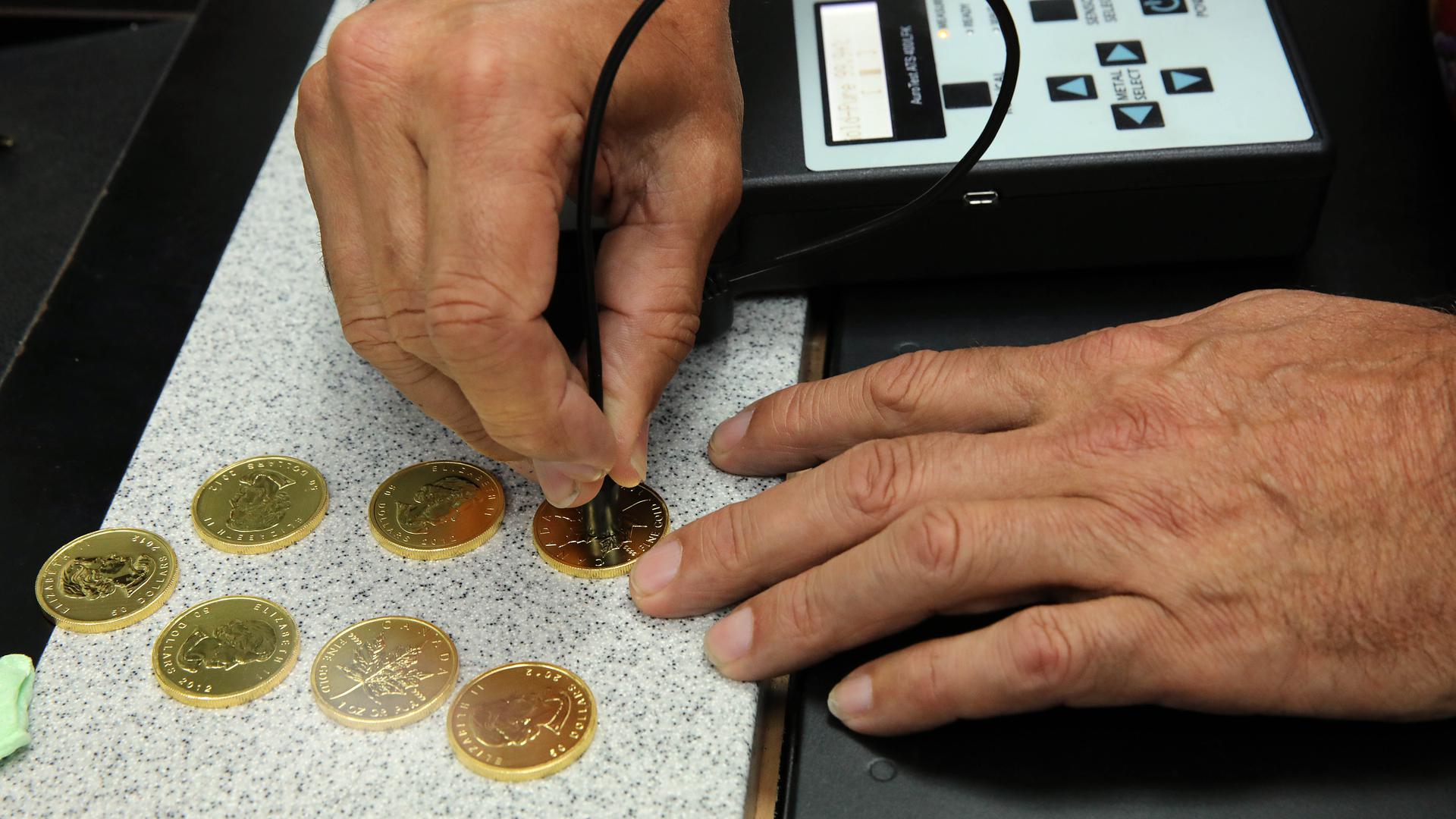 Heinz Schmalzried prüft den Goldgehalt von Münzen mit einem Gerät, das die elektrische Leitfähigkeit des Metalls misst.