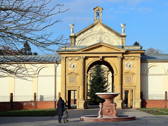 Am  12.12.2022 passiert eine Besucherin des Karlsruher Hauptfriedhofs den großen Christbaum am Haupteingang.
