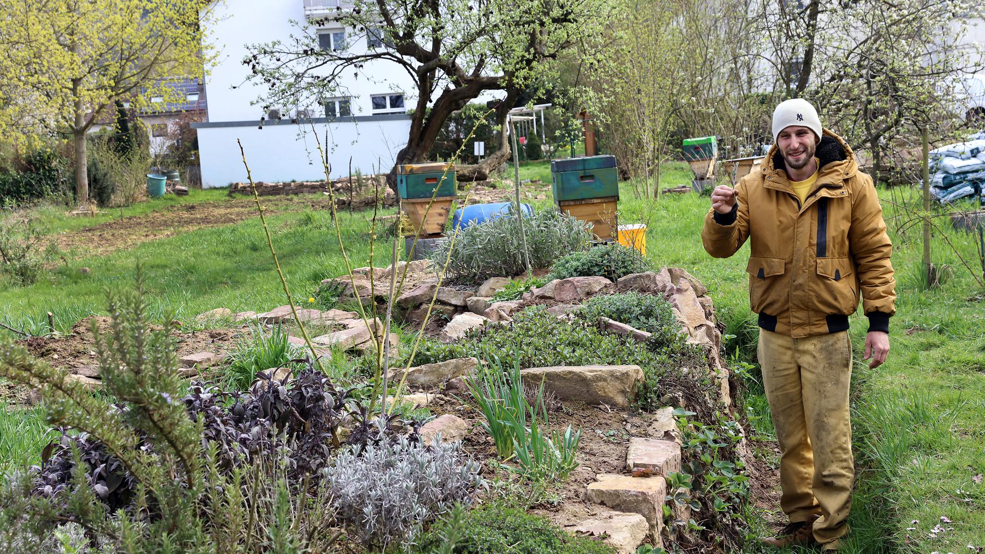 Marc La Fontaine steht in seinem Garten neben seiner Trockenmauer