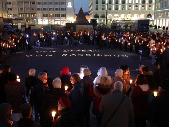 Menschen stehen mit Kerzen um die Pyramide in Karlsruhe