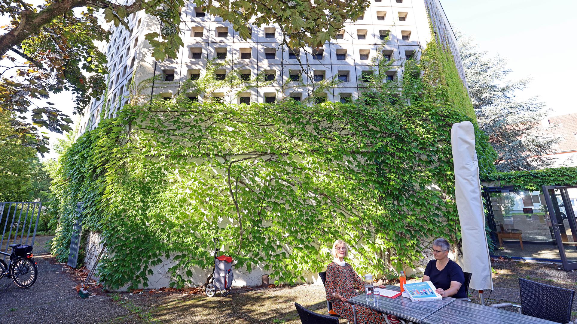 An einem Gartentisch vor dem Turm der Lukaskirche sitzen zwei Frauen mit einer Pappschatulle.