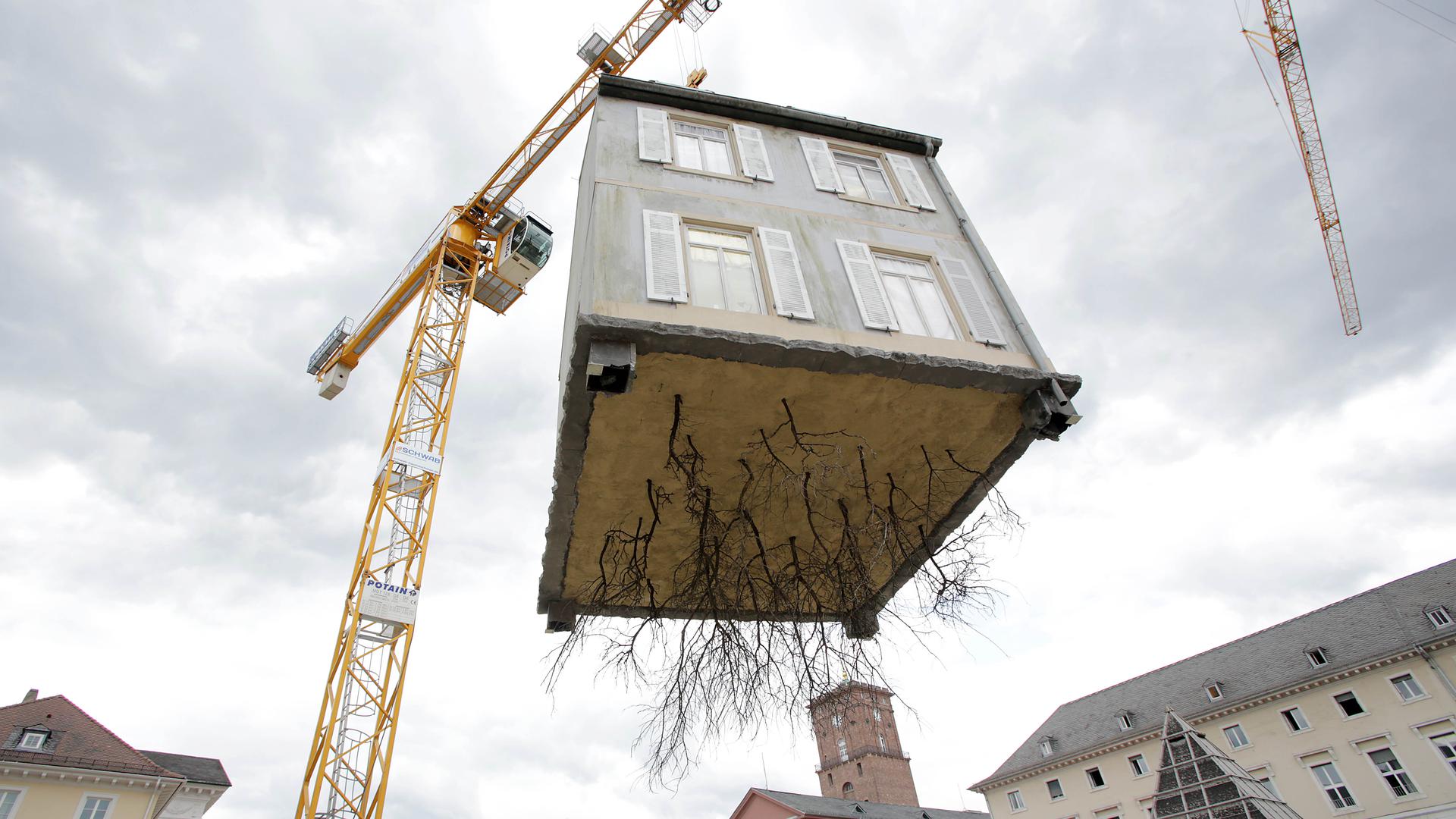 Ein Hingucker: Ein entwurzeltes Haus schwebt im Sommer 2015 über dem Karlsruher Marktplatz. Urheber der Kunstaktion ist das ZKM. 