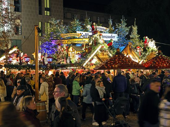 Besucher des Karlsruher Weihnachtsmarkts stehen vor dem Stand „Kofflers Hüttenzauber“.